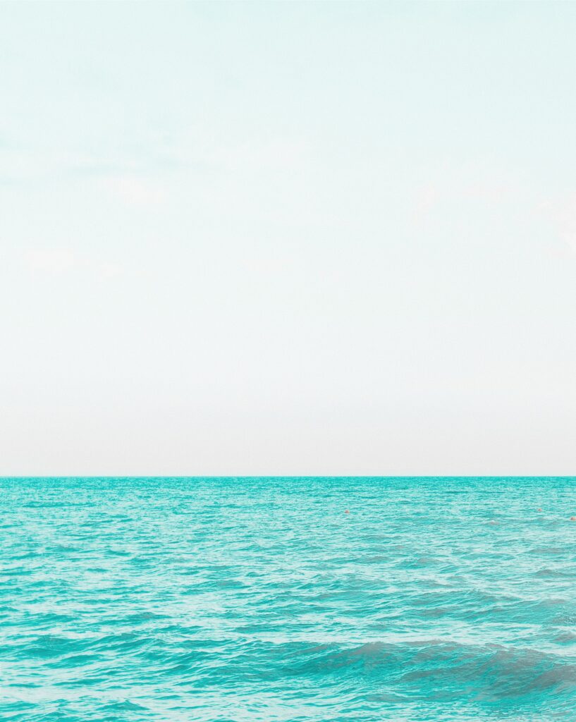 Minimalist sea wallpaper with gentle waves and pastel sky in soft blue and turquoise tones