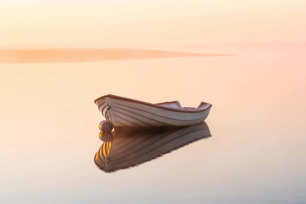 Tranquil Minimalist Wallpaper: Rowboat at Sunrise on Calm Lake