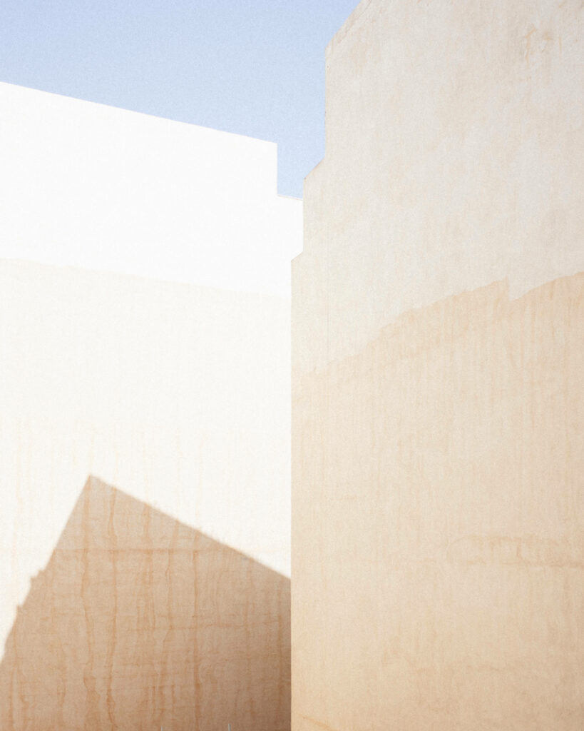 Serene Minimalist Wallpaper: Sunlit Beige Walls & Clear Blue Sky