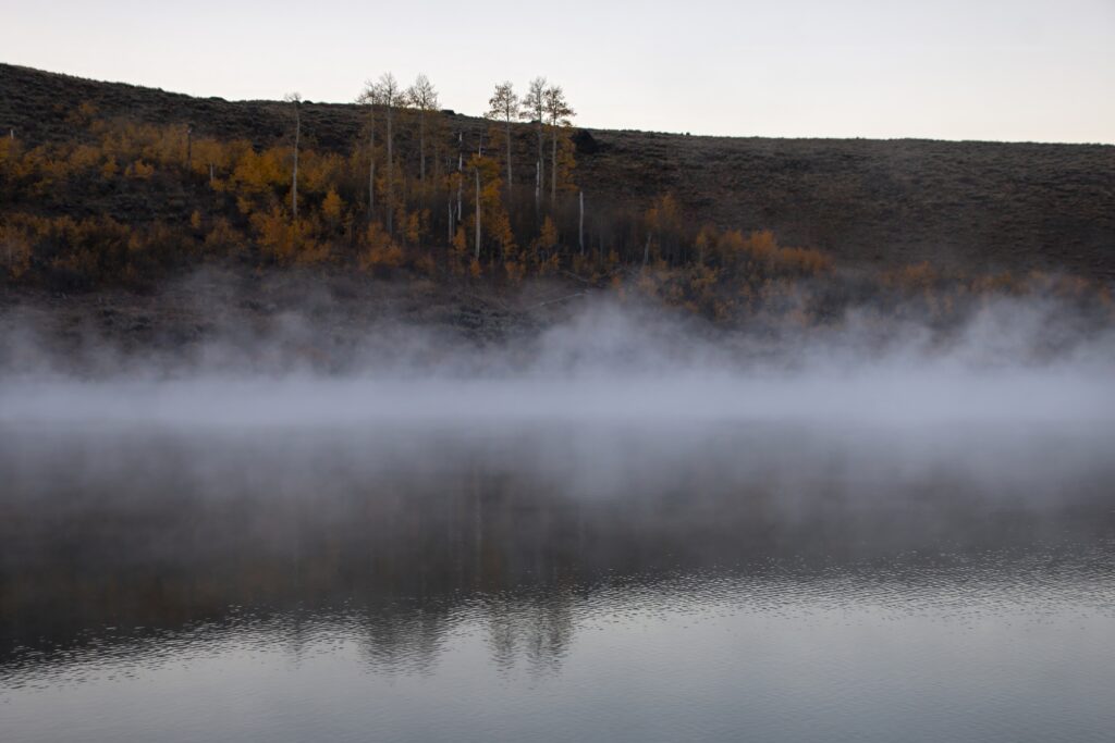 Serene autumn river landscape with morning fog golden trees hillside natural wallpaper background