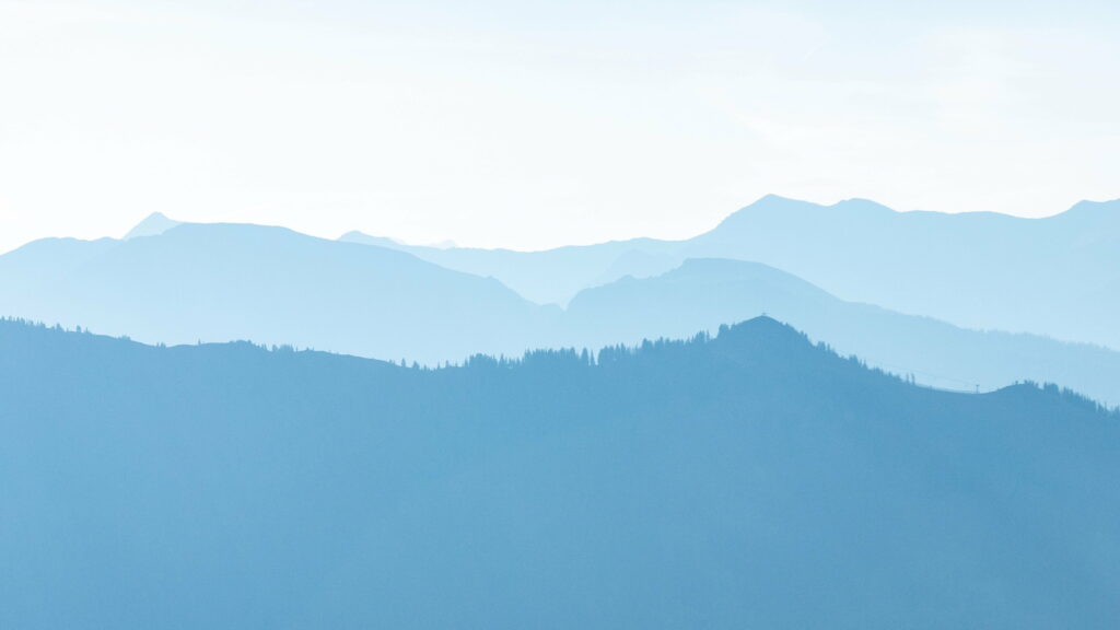 Minimalist mountain landscape wallpaper with soft morning light and calming blue layered peaks