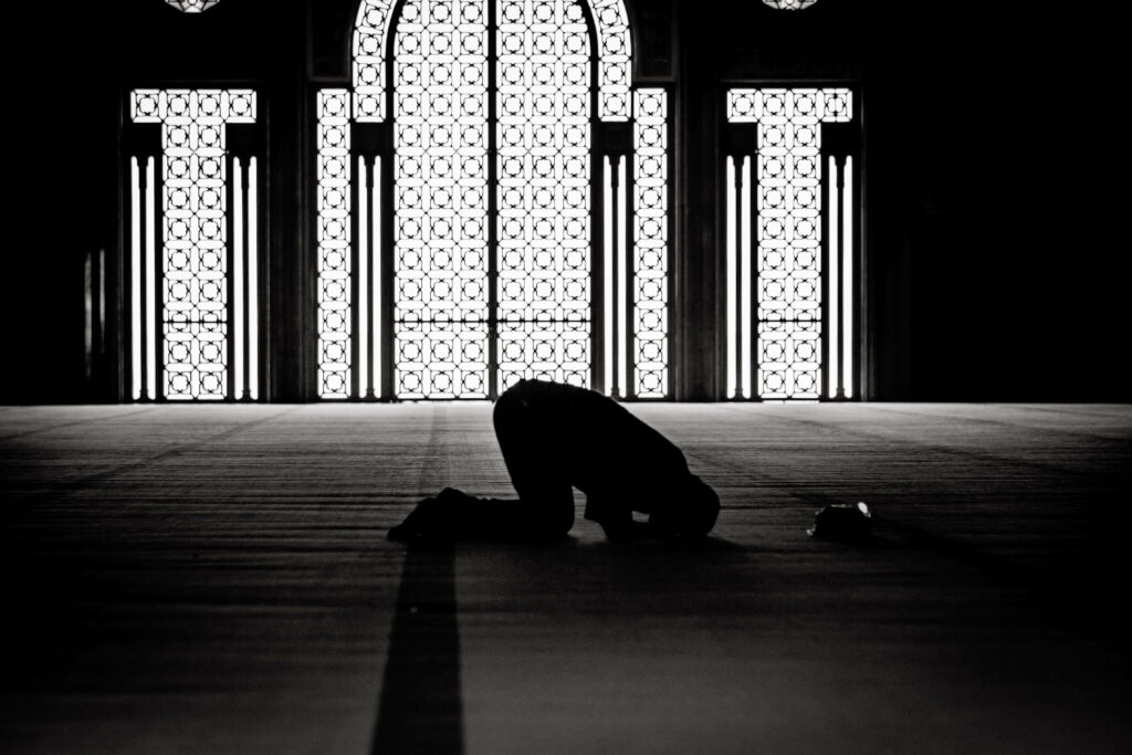 Serene Mosque Interior: Solitary Prayer Amidst Intricate Designs Wallpaper