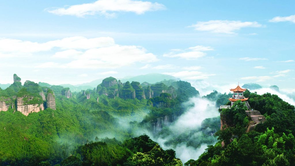 Traditional pavilion on misty Mount Danxia red sandstone cliffs with lush green landscape wallpaper