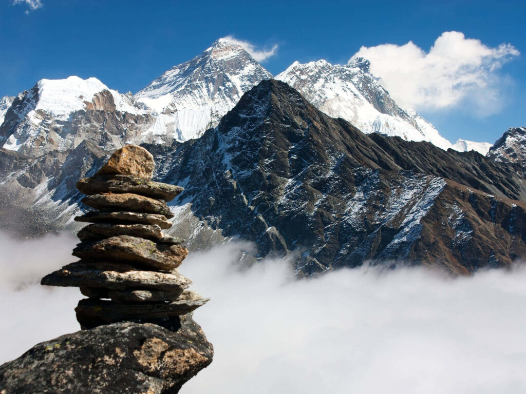 Serene Rock Stack Wallpaper: Snow-Capped Peaks & Cloud Sea Backdrop