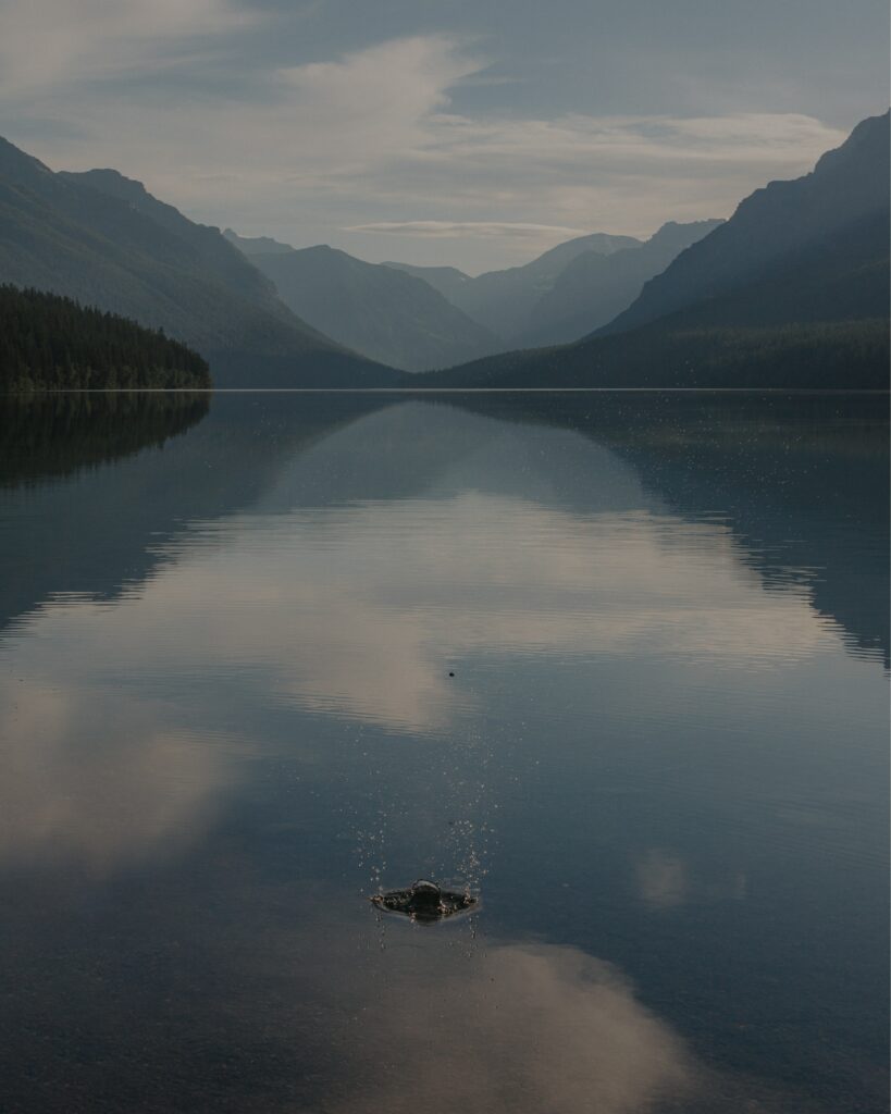 Serene mountain lake with fog and splash reflecting blue sky peaceful nature wallpaper background