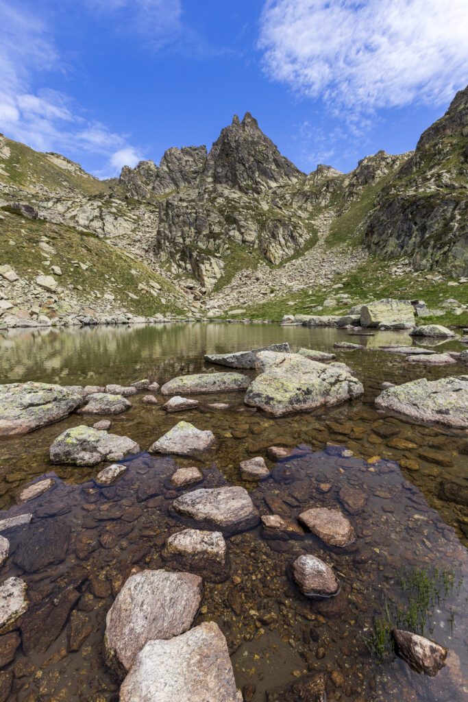 Breathtaking mountain lake landscape with clear water reflecting blue sky and rugged rocks Wallpaper