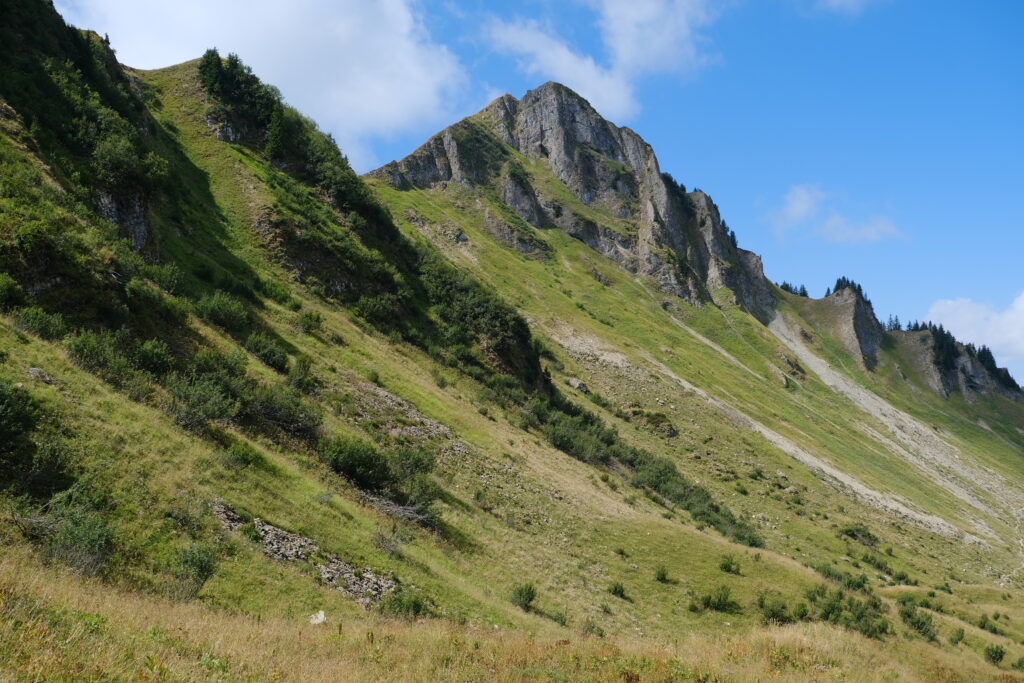 Scenic mountain landscape with rugged rocks steep grassy slope and vibrant blue sky wallpaper