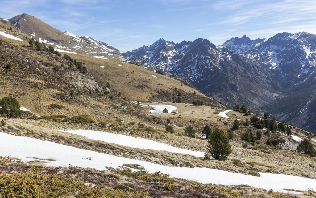 Snow-capped mountain landscape with melting snow green bushes and bright blue sky highlands view Wallpaper