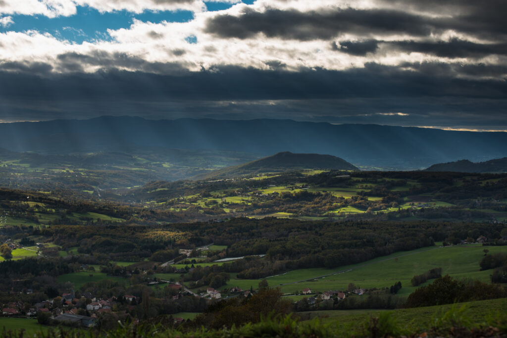 Breathtaking mountain landscape with green valley village under dramatic overcast sky wallpaper