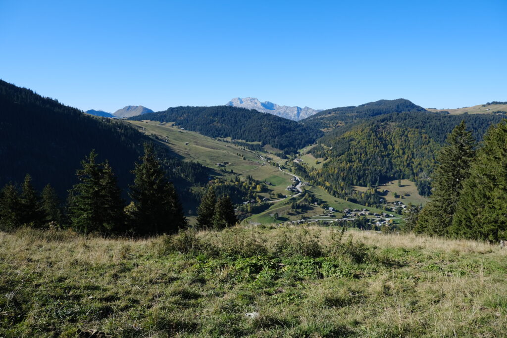 Serene mountain landscape with lush green valley village forested hills and clear blue sky wallpaper