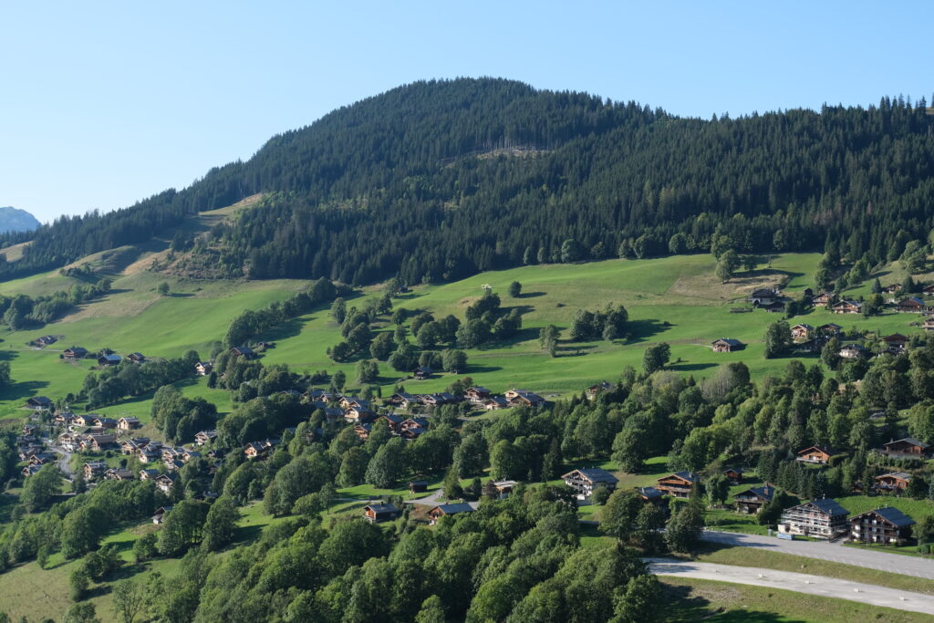 Serene mountain landscape with lush green valley charming village and vibrant forested hills wallpaper