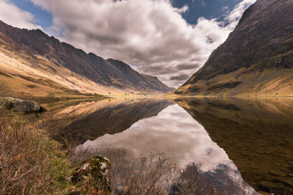 Serene mountain landscape with rugged peaks calm lake reflections and soft earthy tones wallpaper