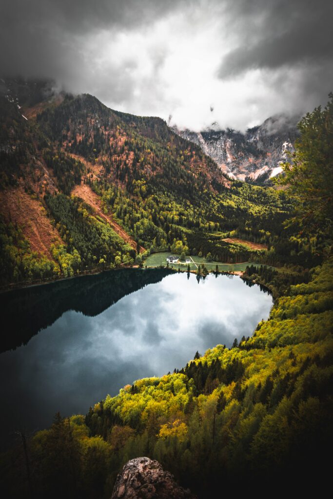 Serene mountain landscape wallpaper with lake reflection lush trees and cozy lakeside house