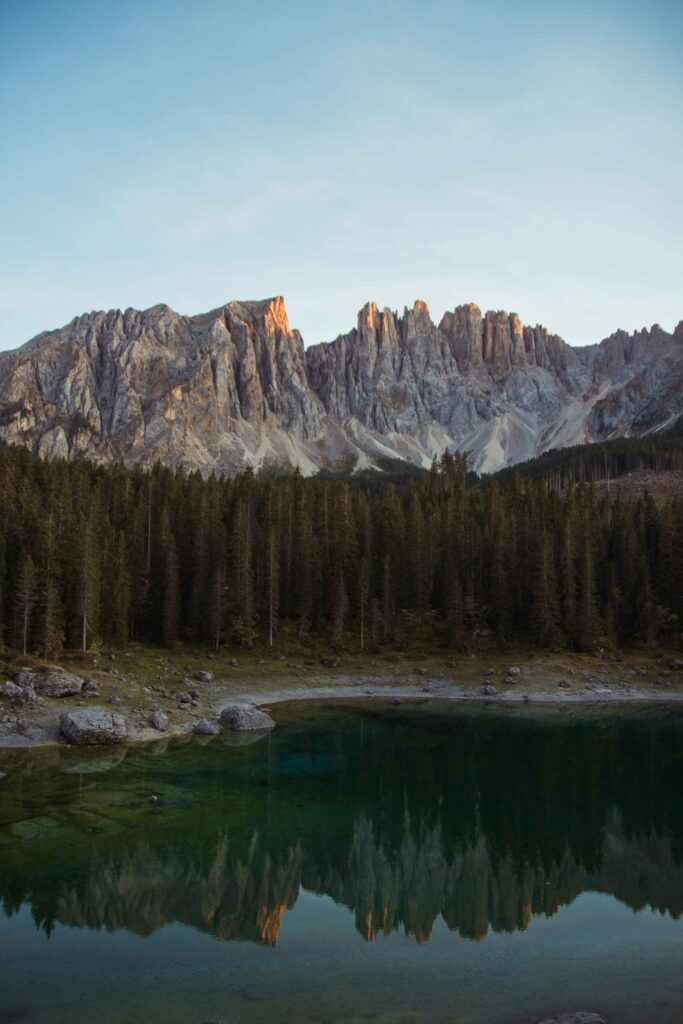 Serene mountain landscape with rugged peaks pine trees and calm reflective lake wilderness wallpaper