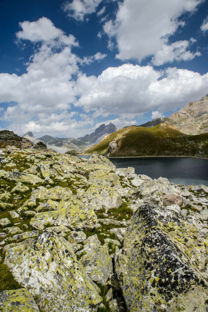 Serene mountain landscape with lichen-covered rocks grassy hills calm water and cloudy sky wallpaper