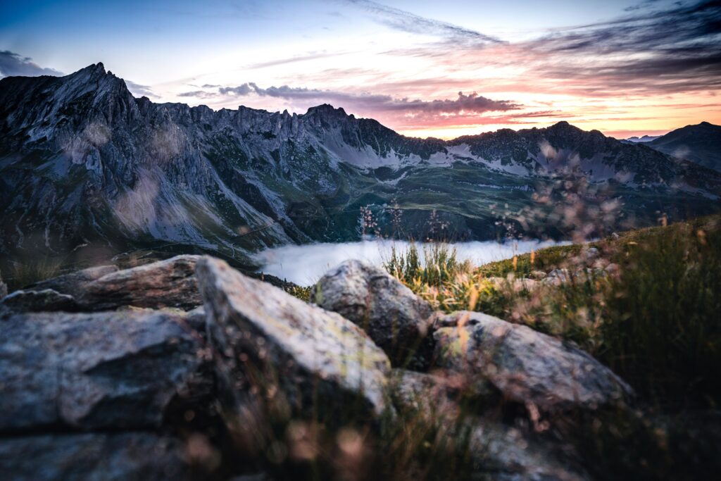 Serene mountain landscape at dusk with rugged rocks misty lake and colorful sky wallpaper background