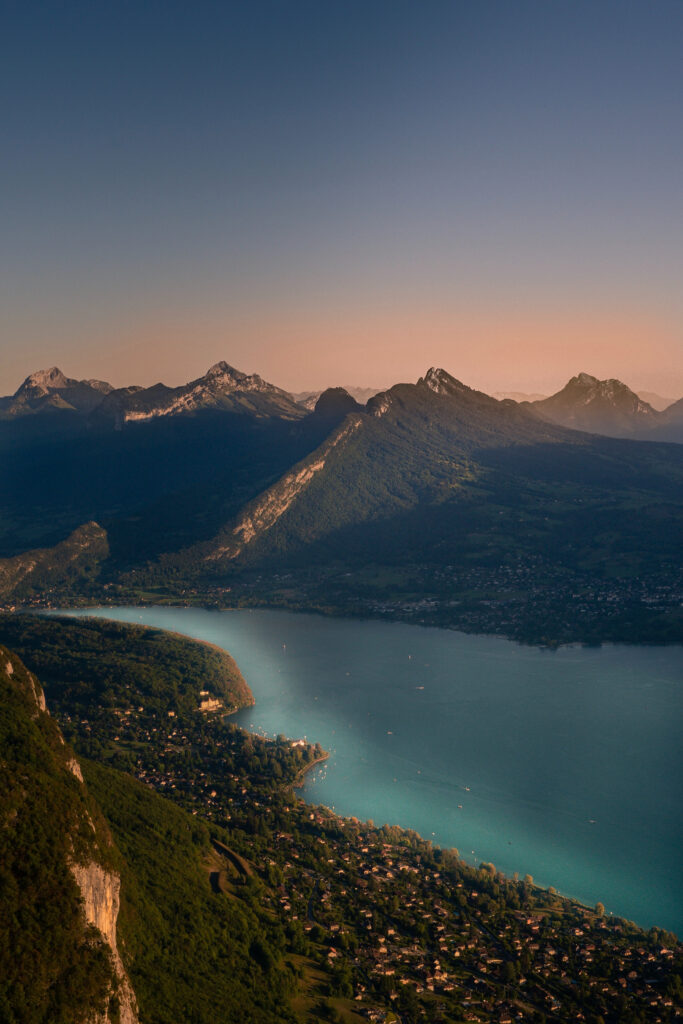 Aerial view of serene mountain range turquoise lake lush forests and warm sunlight landscape wallpaper