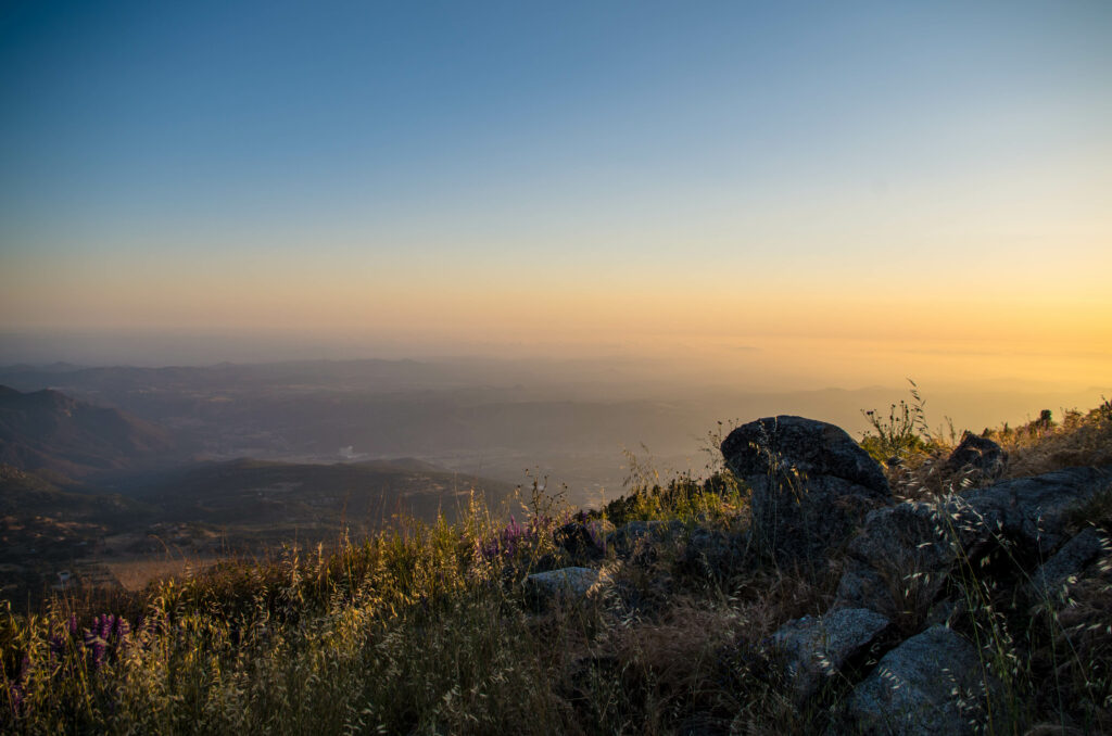 Serene mountain landscape at sunset with rugged stones foreground and golden blue sky background Wallpaper