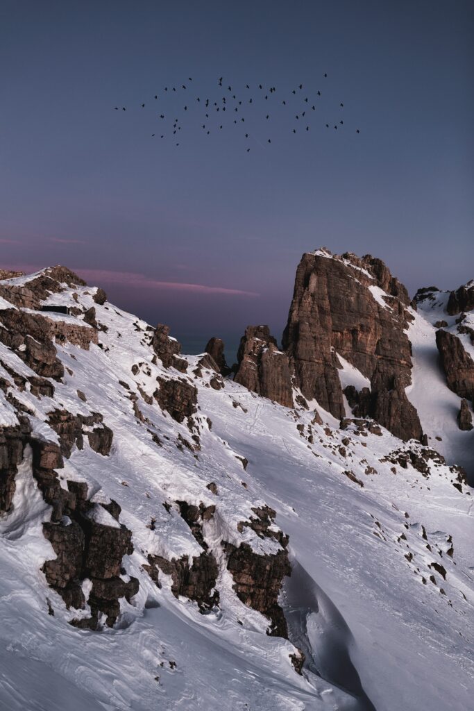 Mountain landscape wallpaper with snow slopes twilight sky and birds soaring in serene nature