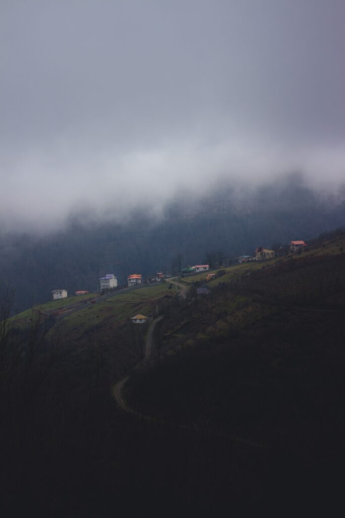 Aerial view of foggy mountainous landscape with scattered small buildings and soft natural light Wallpaper