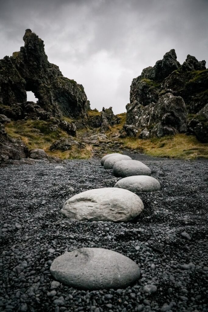 Serene natural landscape with smooth stone path over black gravel and rugged rocks background Wallpaper