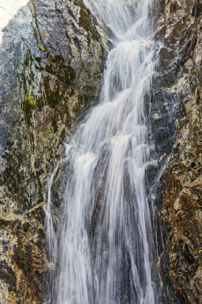 Waterfall cascading over rugged rocks with vibrant earth tones in a serene natural landscape Wallpaper
