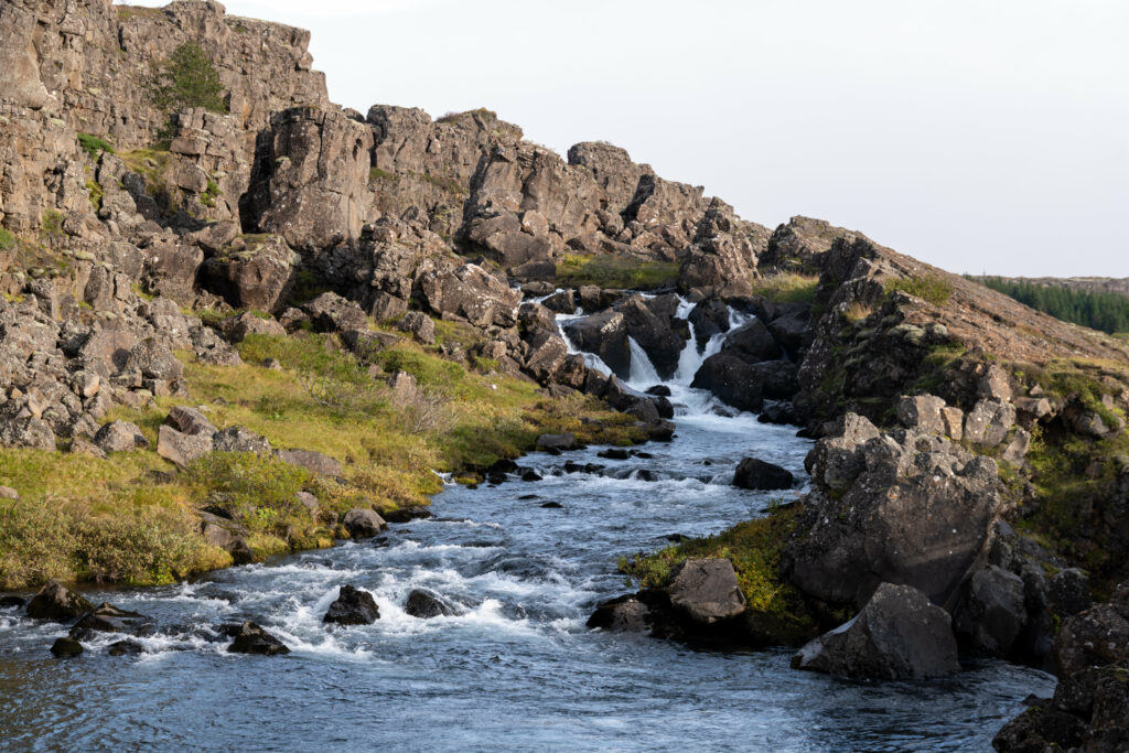Clear stream flowing through rugged rocks with green moss and grass peaceful nature wallpaper