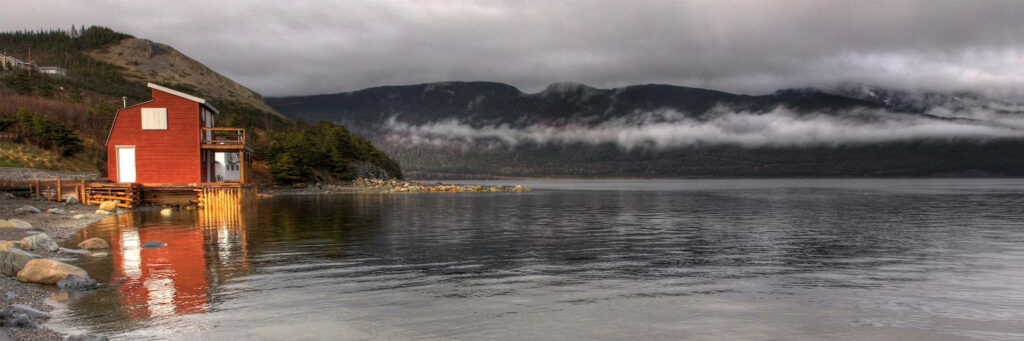 Serene Newfoundland Shoreside Wallpaper: Quaint Red Building & Calm Waters