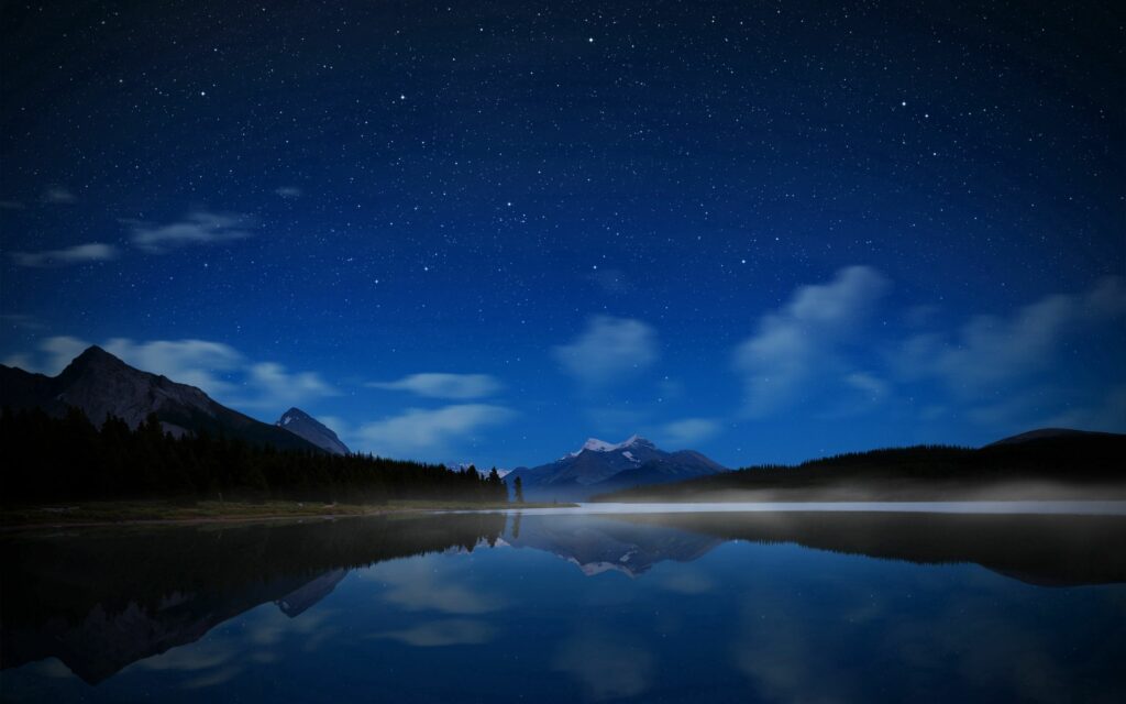 Serene night lake with starry sky reflection foggy calm water and distant mountain landscape wallpaper
