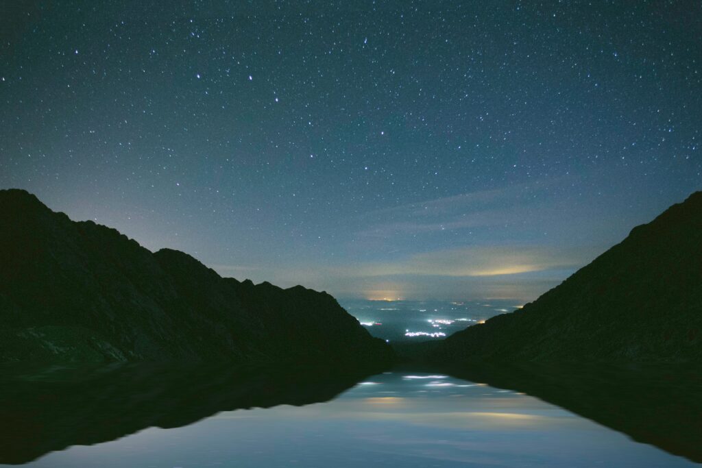 Serene night mountain lake wallpaper with starry sky reflection calm deep blue background