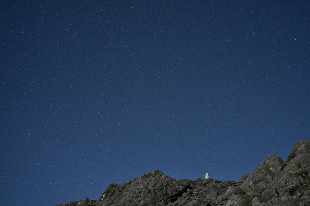 Serene night sky with stars over rugged stones peaceful nature wallpaper background under blue