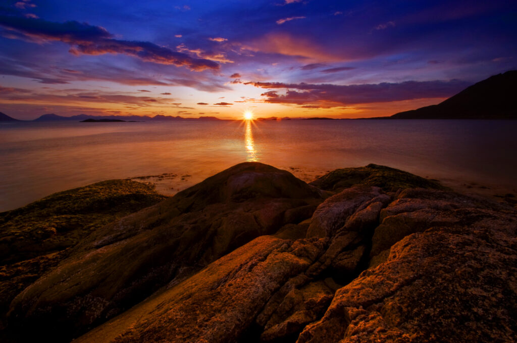 Norway sunset over calm sea with rugged rocks vibrant orange blue sky serene horizon wallpaper