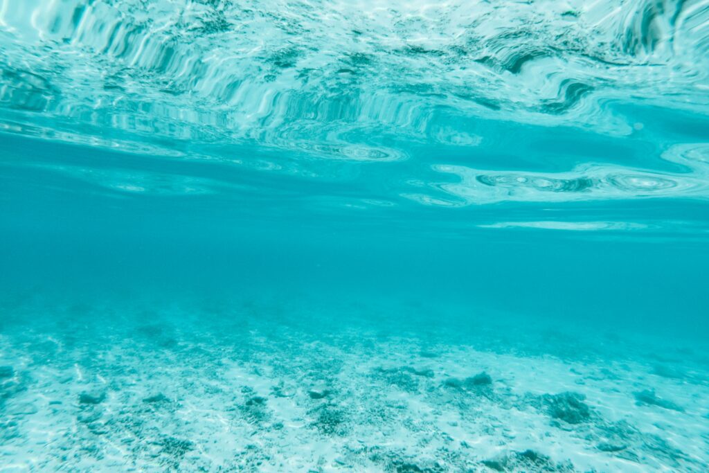 Serene ocean wallpaper with gentle blue waves and textured sandy seabed creating calm depth