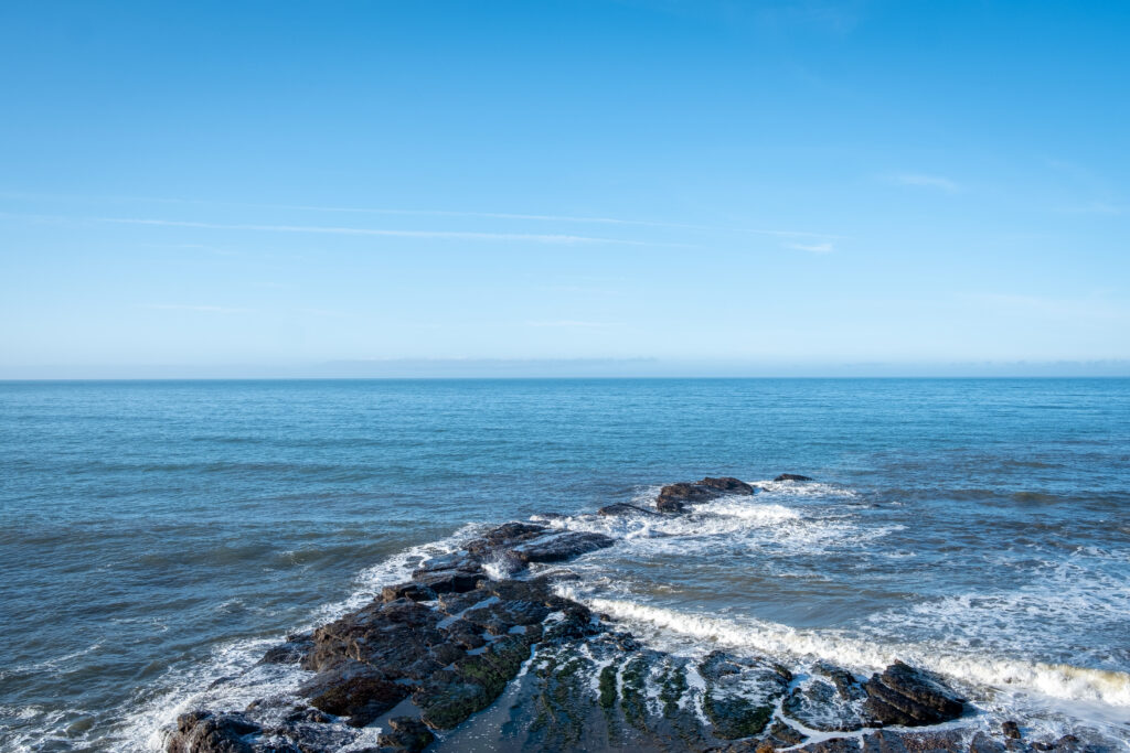 Serene ocean wallpaper with sea foam on rugged reef under bright blue sky capturing tranquility