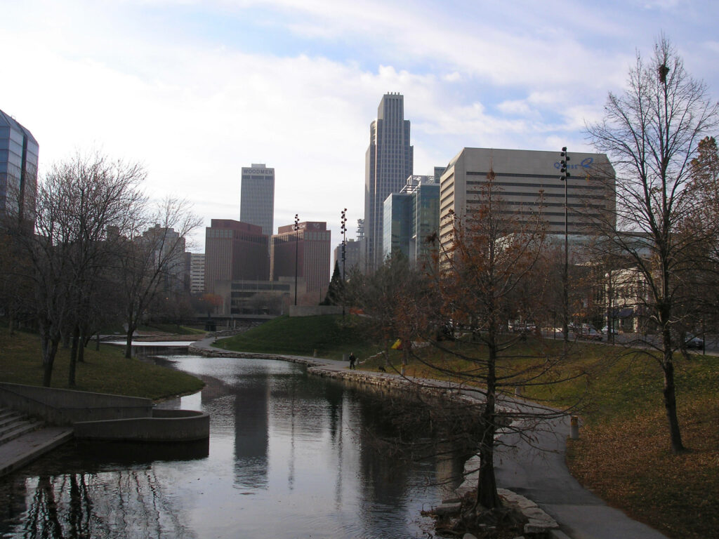 Serene Omaha Urban Landscape: Calm River & Modern High-Rises Wallpaper