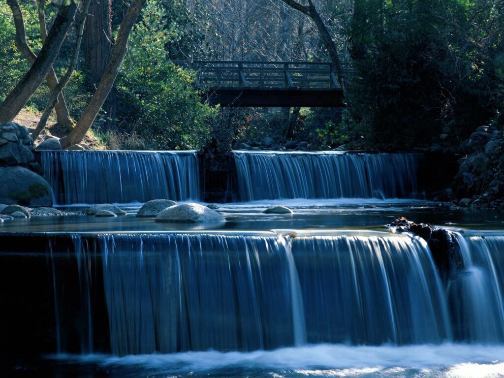 Oregon waterfall with wooden bridge lush green forest and smooth flowing water wallpaper background