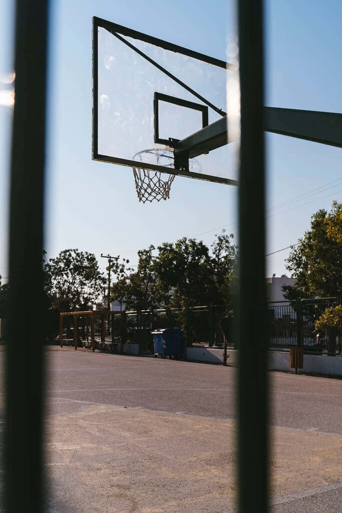 Serene Outdoor Basketball Court Through Fence – Nature Wallpaper