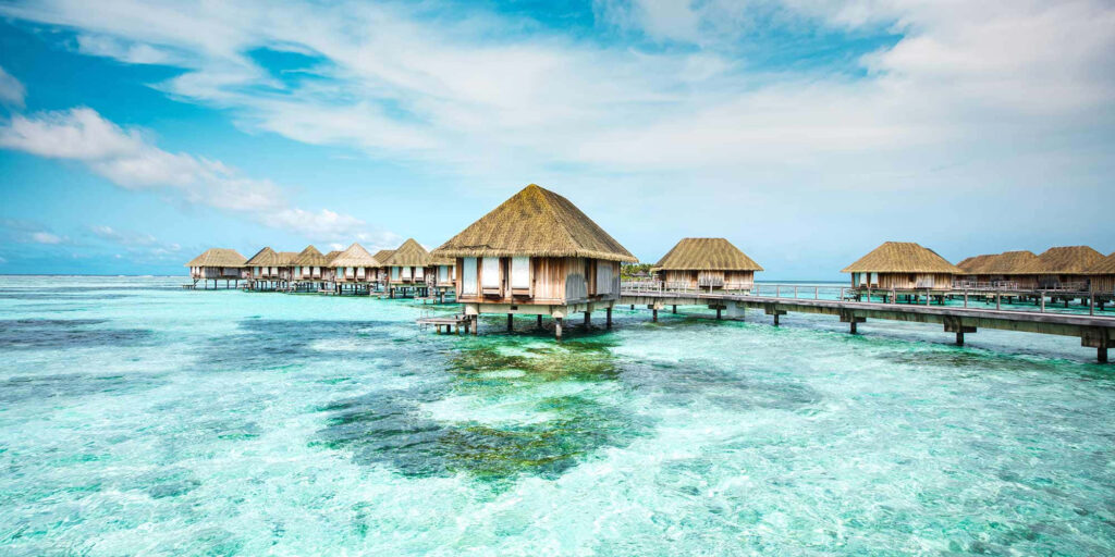 Serene Overwater Huts Wallpaper: Crystal-Clear Waters & Bright Sky