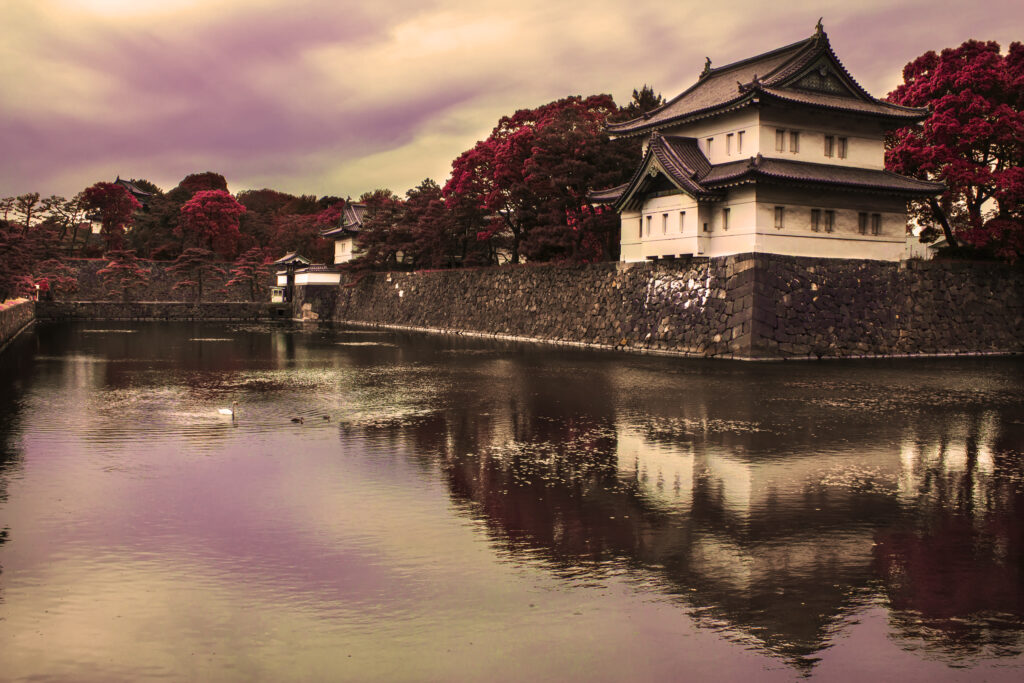 Traditional pagoda by calm moat with red trees and twilight sky reflecting serene landscape wallpaper