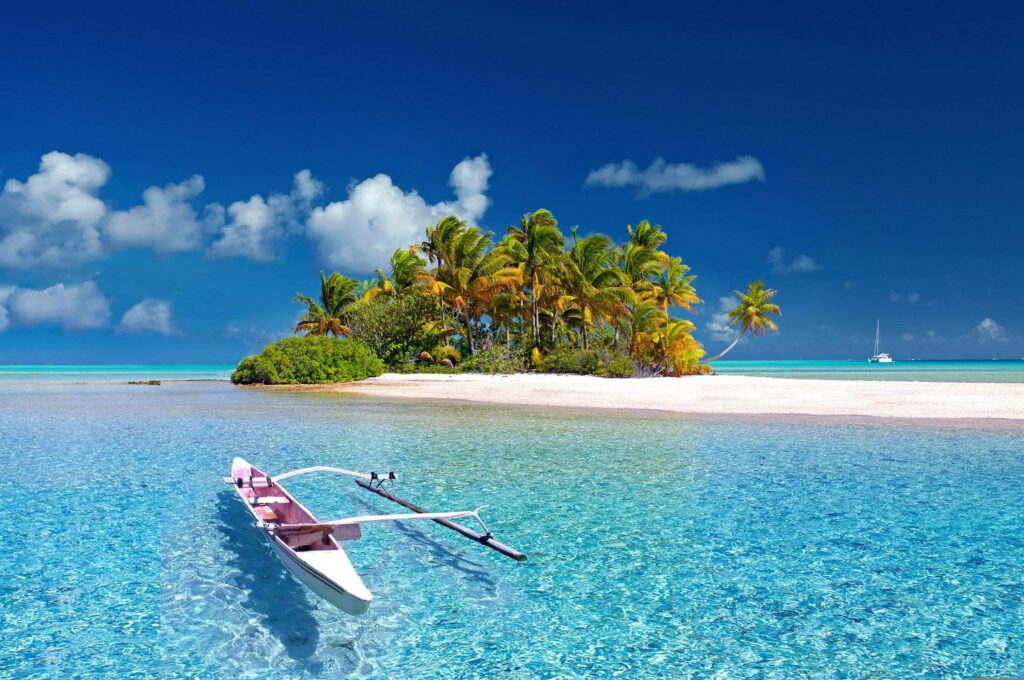 Paradise Found: Stunning HD Wallpaper of a Boat on Azure Waters with a Palm-fringed Sand Island, Beneath a Vivid Blue Sky