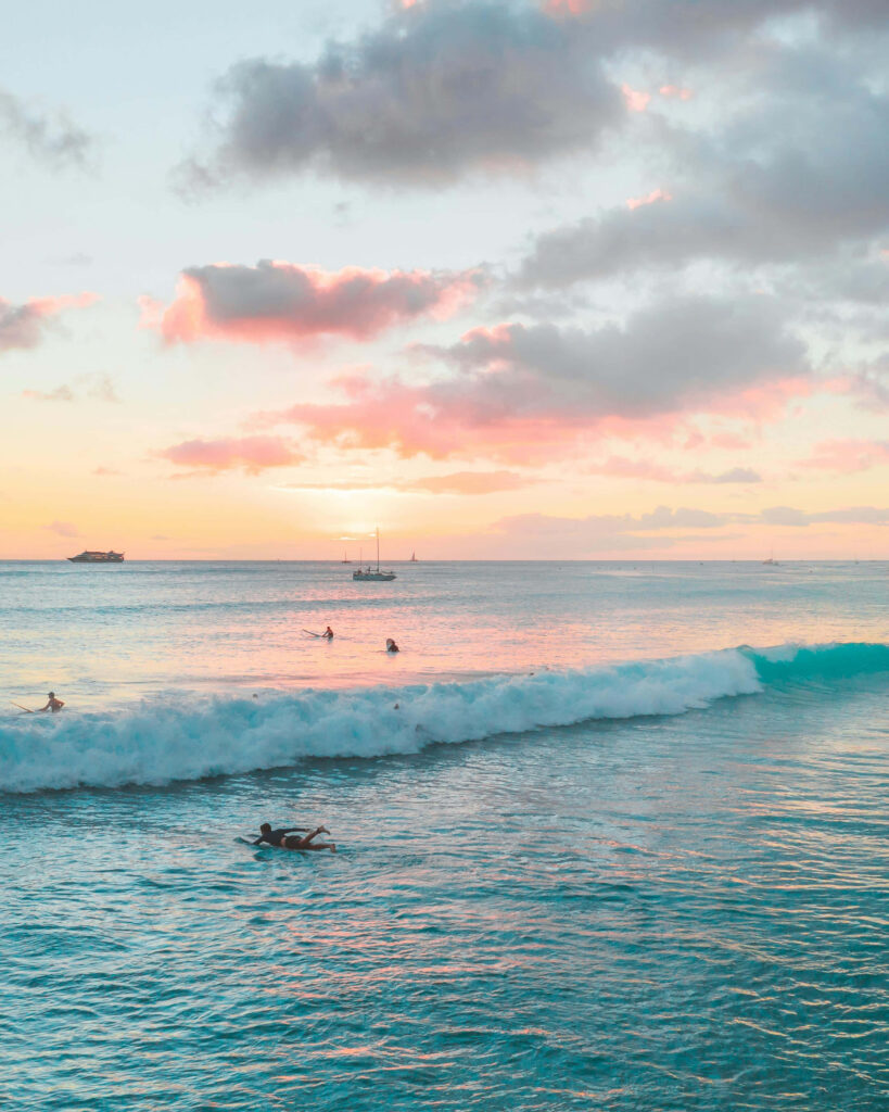 Serene Pastel Sunset Wallpaper: Tranquil Ocean and Surfers Scene
