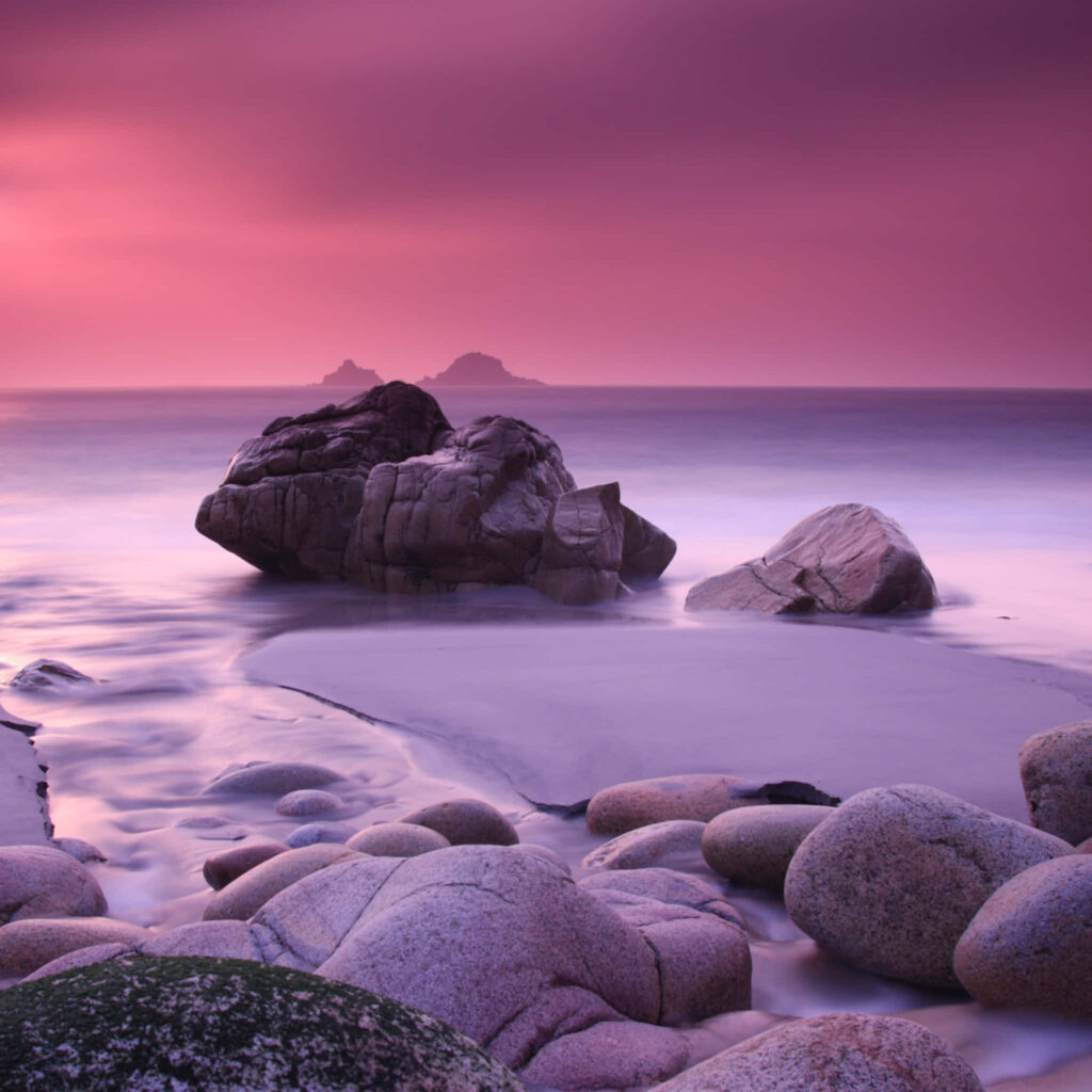 Serene Pink Beach Sunset Wallpaper with Smooth Rocks & Gentle Waves