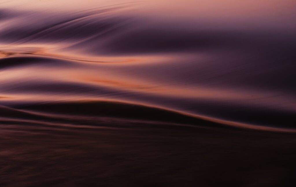 Abstract sea wallpaper with smooth waves and warm golden purple water ripples for calm backgrounds