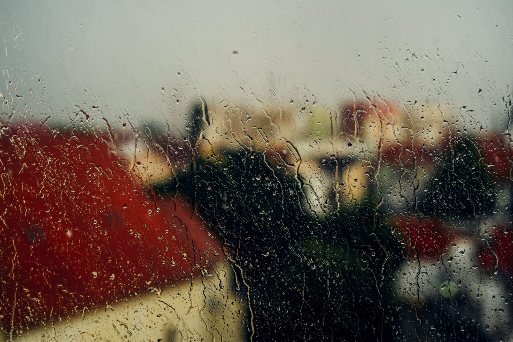 Serene Rain Droplet Wallpaper: Blurred View of Red-Roofed Buildings