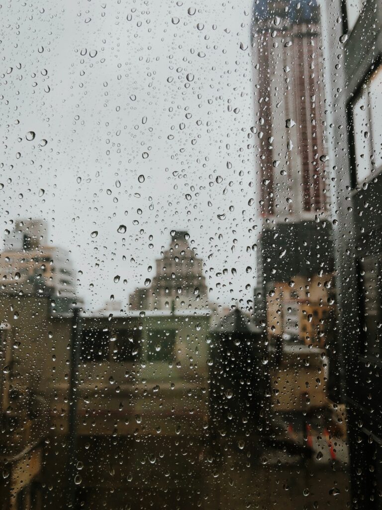 Serene Wallpaper: Raindrops on Glass with Blurred Cityscape Background
