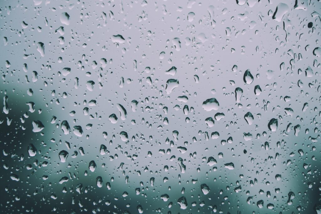 Serene Raindrop Wallpaper: Close-Up on Glass with Nature Background