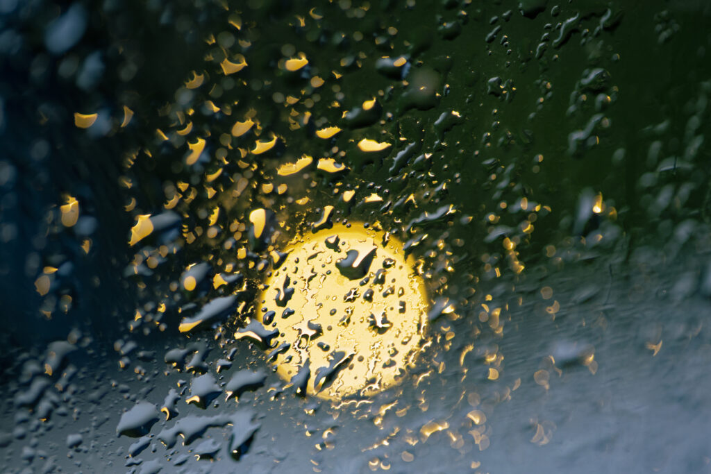 Serene Raindrops on Glass: Macro Wallpaper with Soft Glowing Light