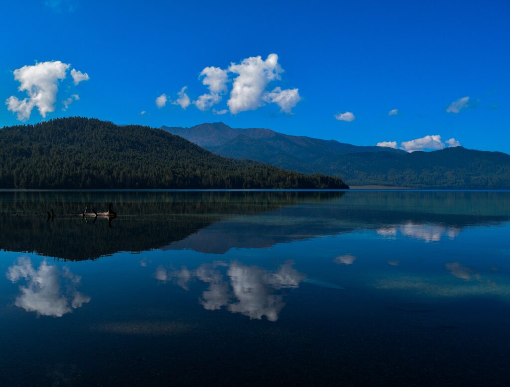 Serene Rara Lake Nepal with deep blue waters reflecting clouds and pine-covered hills wallpaper