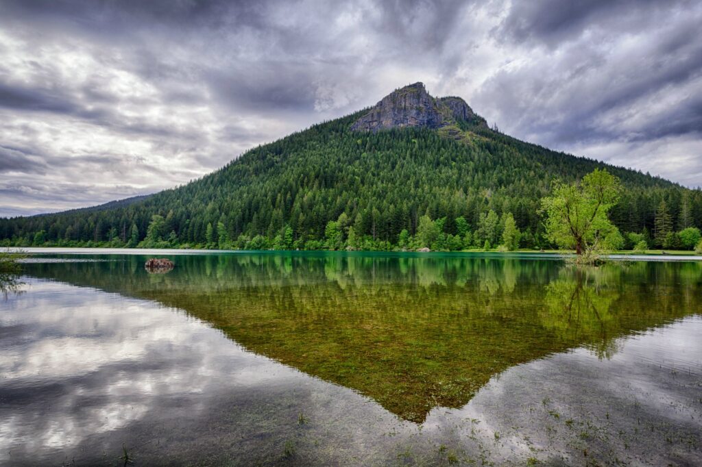 Rattlesnake Ridge Washington with lush trees and calm lake reflecting dramatic cloudy sky wallpaper