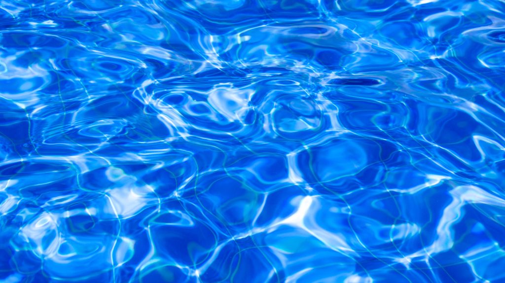 Rippling swimming pool water with deep blue hues and bright sunlight reflections tranquil wallpaper